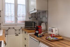 a kitchen with a counter with a toaster and a microwave at Élégance Parisienne : Confort & Connectivité avec Wifi & Netflix Inclus in Deuil-la-Barre