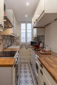 a kitchen with white cabinets and a washer and dryer at Élégance Parisienne : Confort & Connectivité avec Wifi & Netflix Inclus in Deuil-la-Barre