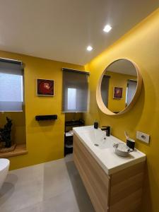a yellow bathroom with a sink and a mirror at ERASMO 19 Luxury Home in Catania
