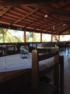 a dining room with a table and chairs and windows at Pousada Zekas in Jacumã