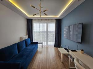 a living room with a blue couch and a table at Nowoczesny i komfortowy apartament przy ulicy Kurpiowskiej blisko centrum miasta in Siedlce
