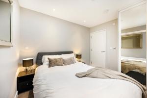 a bedroom with a large white bed and a mirror at New Modern 1 Bed Flat Great Location Piccadilly Line in Hounslow