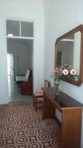 a room with a mirror and a table with flowers on it at Casa Almirante Reis in Olhão