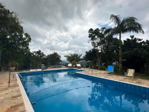 a blue swimming pool with chairs and palm trees at Rancho NPI in Guarulhos