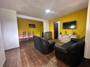 ein Wohnzimmer mit zwei schwarzen Stühlen und einem Flachbild-TV in der Unterkunft Rancho NPI in Guarulhos