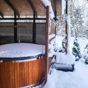 bañera de hidromasaje cubierta de nieve junto a una valla de madera en Dom caloroczny w Szymbarku, en Szymbark