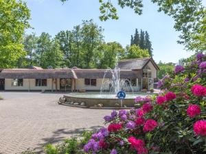 a fountain in front of a building with flowers at Cozy home with lots of privacy, in the forest in De Bult