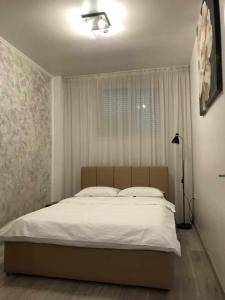 - une chambre avec un grand lit blanc et une fenêtre dans l'établissement Modern & Elegant Luxury Apartament, à Craiova
