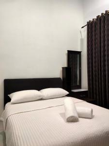 ein Bett mit einer weißen Decke und Kissen darauf in der Unterkunft COZY CR Guesthouse Nilai Pajam with Self Check-In in Nilai