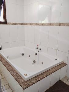 a white bath tub in a white tiled bathroom at Pousada Recanto do Chalé Ltda in Macacos