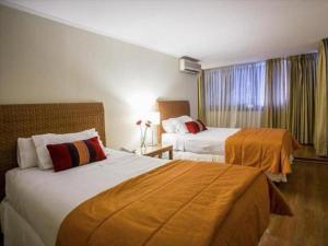 a hotel room with two beds and a window at Suites El Golf San Sebastian 2711 Las Condes in Santiago