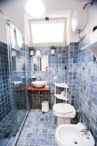 La salle de bains est pourvue de carrelage bleu, de toilettes et d'un lavabo. dans l'établissement Chiaia Bridge B&B, à Naples
