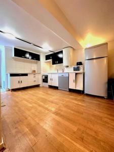 eine große Küche mit weißen Geräten und Holzböden in der Unterkunft Maison Jardin&Terrasse 15min de Paris in Houilles