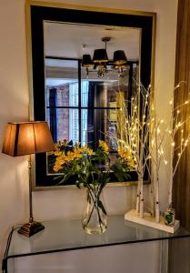 einen Spiegel und eine Vase mit Blumen auf dem Tisch in der Unterkunft Cocoa Isabella - River fronted with secure parking in York