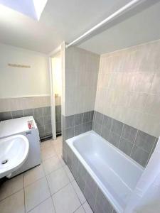 ein Badezimmer mit einer weißen Badewanne und einem Waschbecken in der Unterkunft L'adorable Maison des Clients 15min de Paris in Houilles
