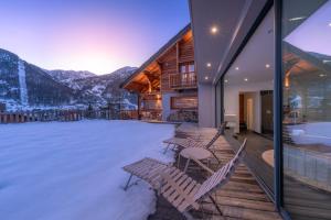 una terraza con sillas, bañera de hidromasaje y montañas en Chalet Snowbird 5 étoiles, Serre-Chevalier, en La Salle-les-Alpes