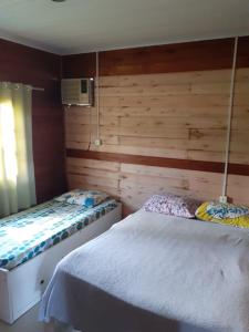 two beds in a room with wooden walls at CASA DE VERANEIO COM PISCINA in São Francisco do Sul