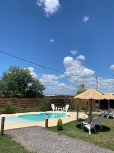 a swimming pool with two chairs and an umbrella at Cabañas Punta Arena in San Pedro