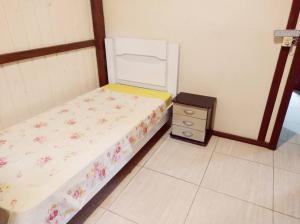 a small bedroom with a bed and a night stand at Aluguel casa temporada praia do rosa in Garopaba