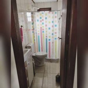 a bathroom with a toilet and a colorful shower curtain at Aluguel casa temporada praia do rosa in Garopaba