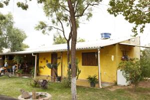 Una casa amarilla con un árbol delante. en Pousada Sitio do Terrao en Três Marias