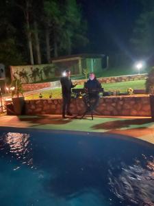 dos hombres sentados en una mesa junto a una piscina por la noche en Mina sweet home apartment, en Skopje