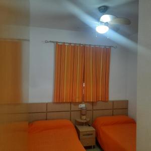 オロペサ・デル・マールにあるApartamento Marina D'Orのベッドルーム1室(ベッド2台付)、窓(オレンジ色のカーテン付)