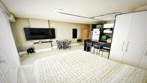 um quarto com uma cama e uma cozinha com uma televisão em 105 Saint Sebastian Flat em Jaraguá do Sul