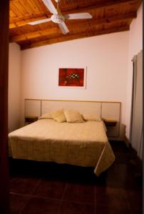 a bedroom with a bed with a painting on the wall at Chalets de la paix in Santa Rosa de Calamuchita