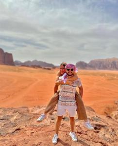 a man and a woman standing on a rock in the desert at Mohammed Wadi Rum Camp in Wadi Rum