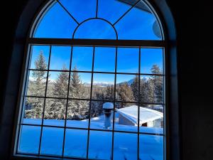 een boogvormig raam met uitzicht op met sneeuw bedekte bomen bij Glacier Dream Escape in Coram