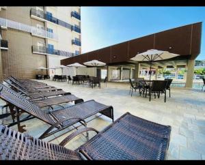 eine Terrasse mit Tischen, Stühlen und Sonnenschirmen in der Unterkunft Spazzio diRoma c/Acqua Park!! in Caldas Novas