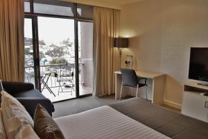 沃加沃加Pavilion Hotel Wagga Wagga的配有床、书桌和电视的酒店房间