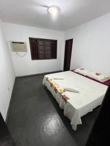ein Schlafzimmer mit einem Bett mit einem Tisch mit Blumen darauf in der Unterkunft Hostel e Restaurante Dona Lu in Itaperuna