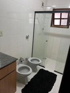 a bathroom with a toilet and a glass shower at Hostel e Restaurante Dona Lu in Itaperuna