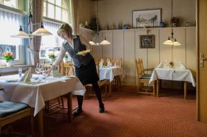 a woman standing at a table in a restaurant at Hotel Wieting in Oldenburg
