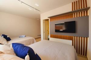 een slaapkamer met 2 bedden en een tv aan de muur bij JPN87 - Duplex em condomínio fechado próx. à praia in Natal