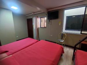 een slaapkamer met twee rode bedden en een raam bij alborada cuenca hospedaje in Cuenca