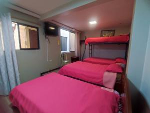 2 camas en una habitación con sábanas rosas en alborada cuenca hospedaje, en Cuenca