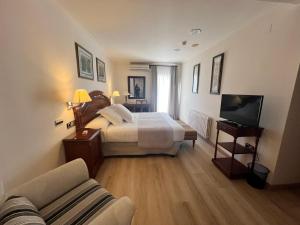 een slaapkamer met een bed en een tv en een bank bij CAN MARLET MONTSENY Hotel Boutique in Montseny
