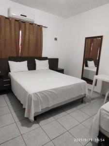 a bedroom with a large white bed and a chair at HOTEL ATLANTA in Paulistana