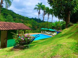 a resort with a swimming pool and palm trees at Pousada Recanto do Chalé Ltda in Macacos