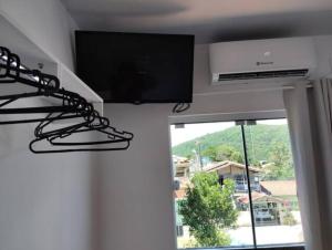 a flat screen tv in a room with a window at HORTA DO TOMATE in Bombinhas