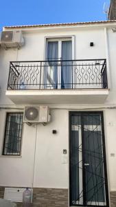 Dieses weiße Gebäude verfügt über einen Balkon und einen Ventilator. in der Unterkunft La casa di Eva in Avola