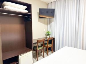 um quarto com uma cama, uma mesa e cadeiras em Presto Hotel em Blumenau