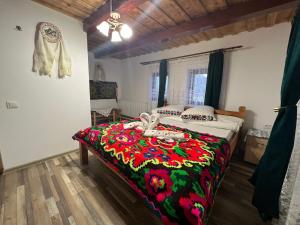 a bedroom with a bed with a colorful blanket at Pensiunea Teodora Breb Maramu in Breb