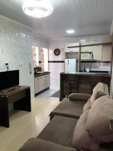 uma sala de estar com um sofá e uma cozinha em Casa com AR COND. em todos os comodos mobiliada em Cascavel