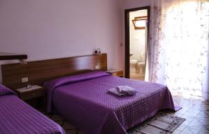 - une chambre avec 2 lits et des draps violets dans l'établissement Agriturismo Perdaba, à Fluminimaggiore