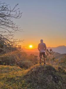 a man standing on a hill looking at the sunset at Pousada Iasbeck in Santa Rita de Jacutinga