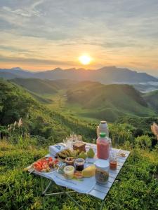a picnic table with food on a hill with the sunset at Pousada Iasbeck in Santa Rita de Jacutinga